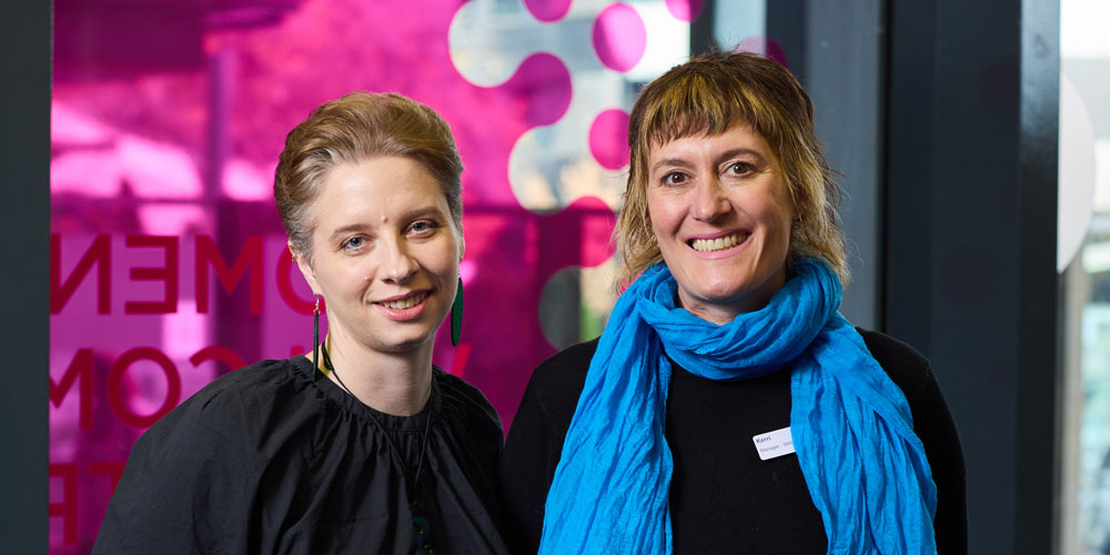 Dr Anna Tottman and Kerri Felemonow are smiling inside the Women's foyer.