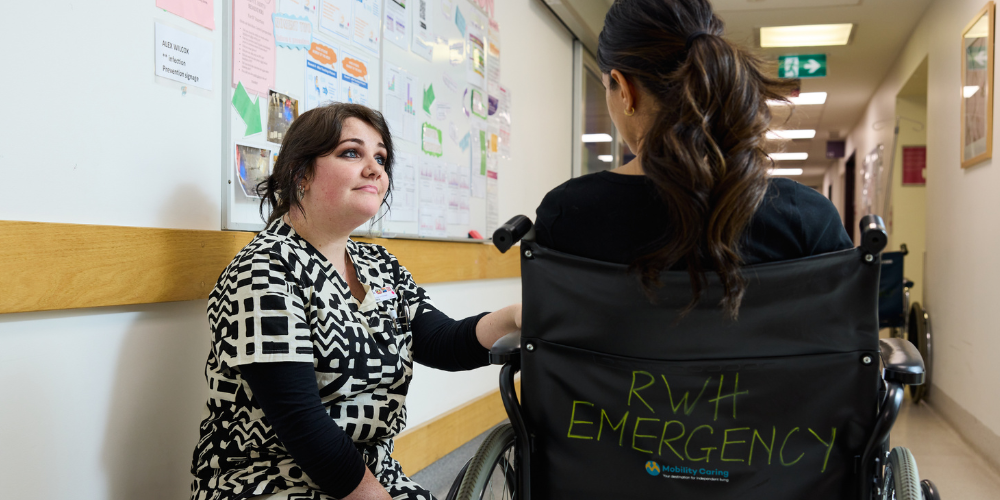 Nurse caring for female patient sitting in a wheelchair with the label: RWH Emergency.
