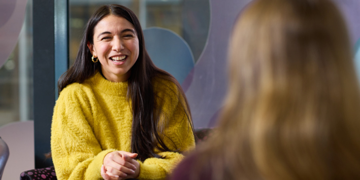 A staff member smiling and talking to a person.