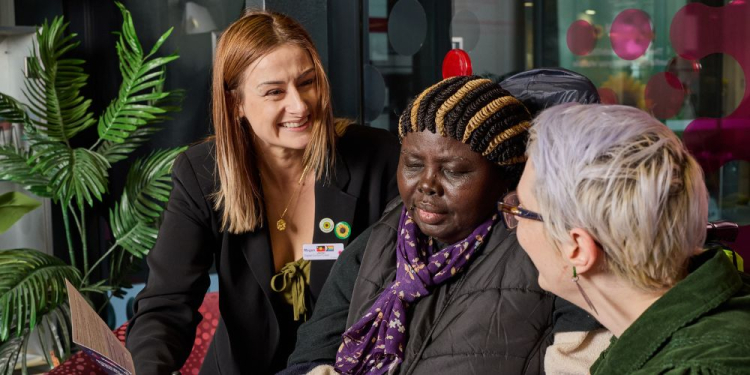 Two staff members of the Women's supporting a woman with a hidden disability.  