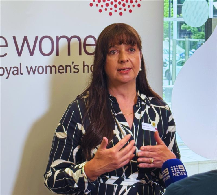 Lisa Lynch chief operations officer standing in front of media banner with news mic in front of her