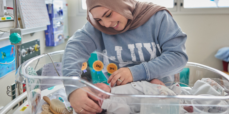 Woman looking lovingly toward a prematurely born baby. 