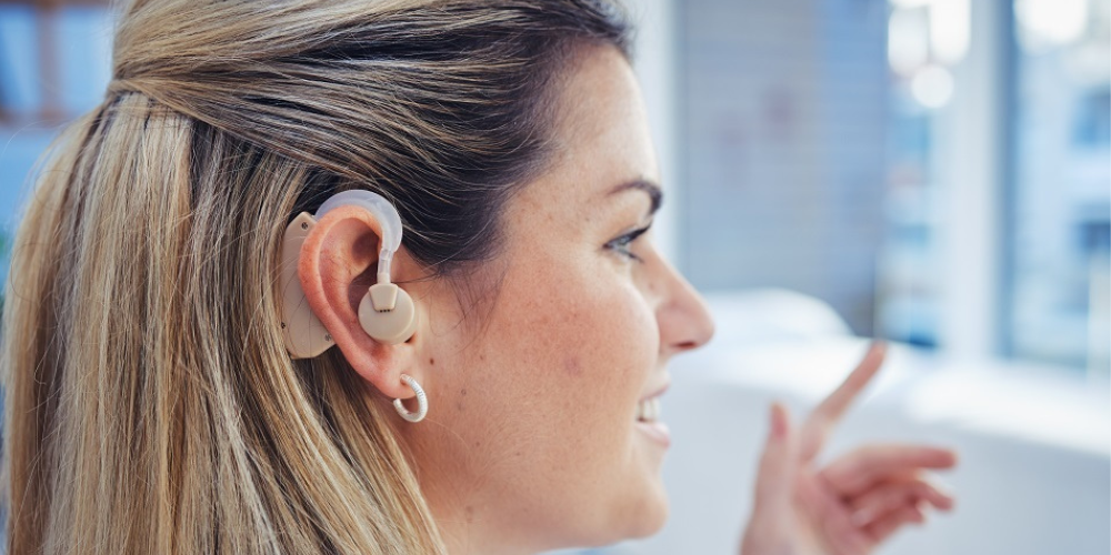Smiling woman and a closeup of her hearing aid